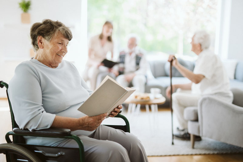 người phụ nữ khuyết tật vui vẻ đọc sách trong viện dưỡng lão