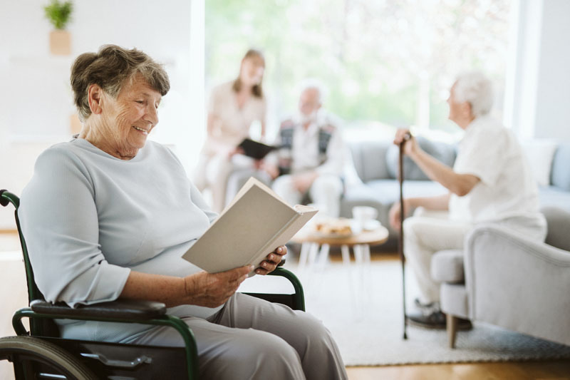 donna disabile felice che legge un libro nella casa di cura