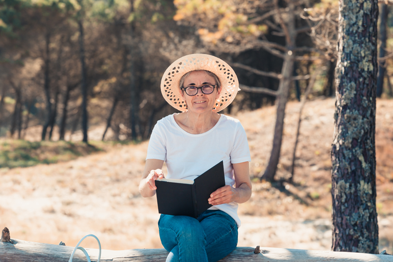 alte Frau, die ein Buch am Strand liest