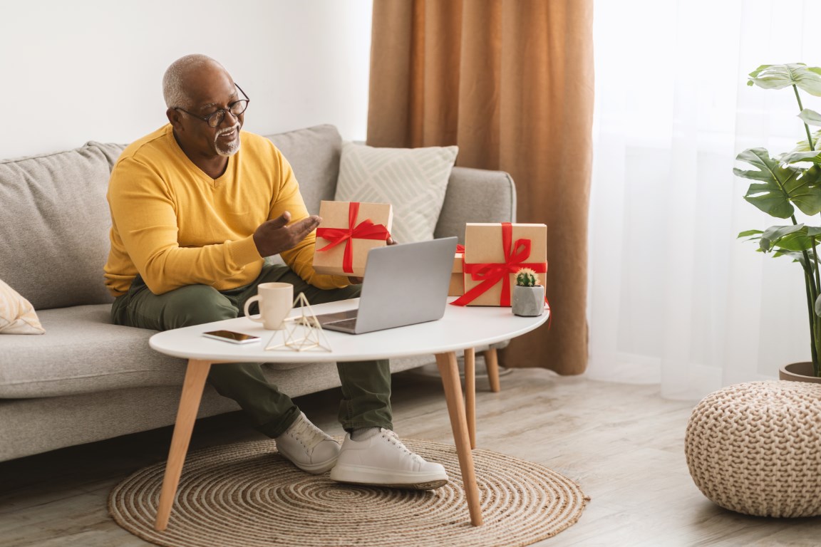 senior black man showing gift to laptop video call 2022 10 07 01 04 22 utc