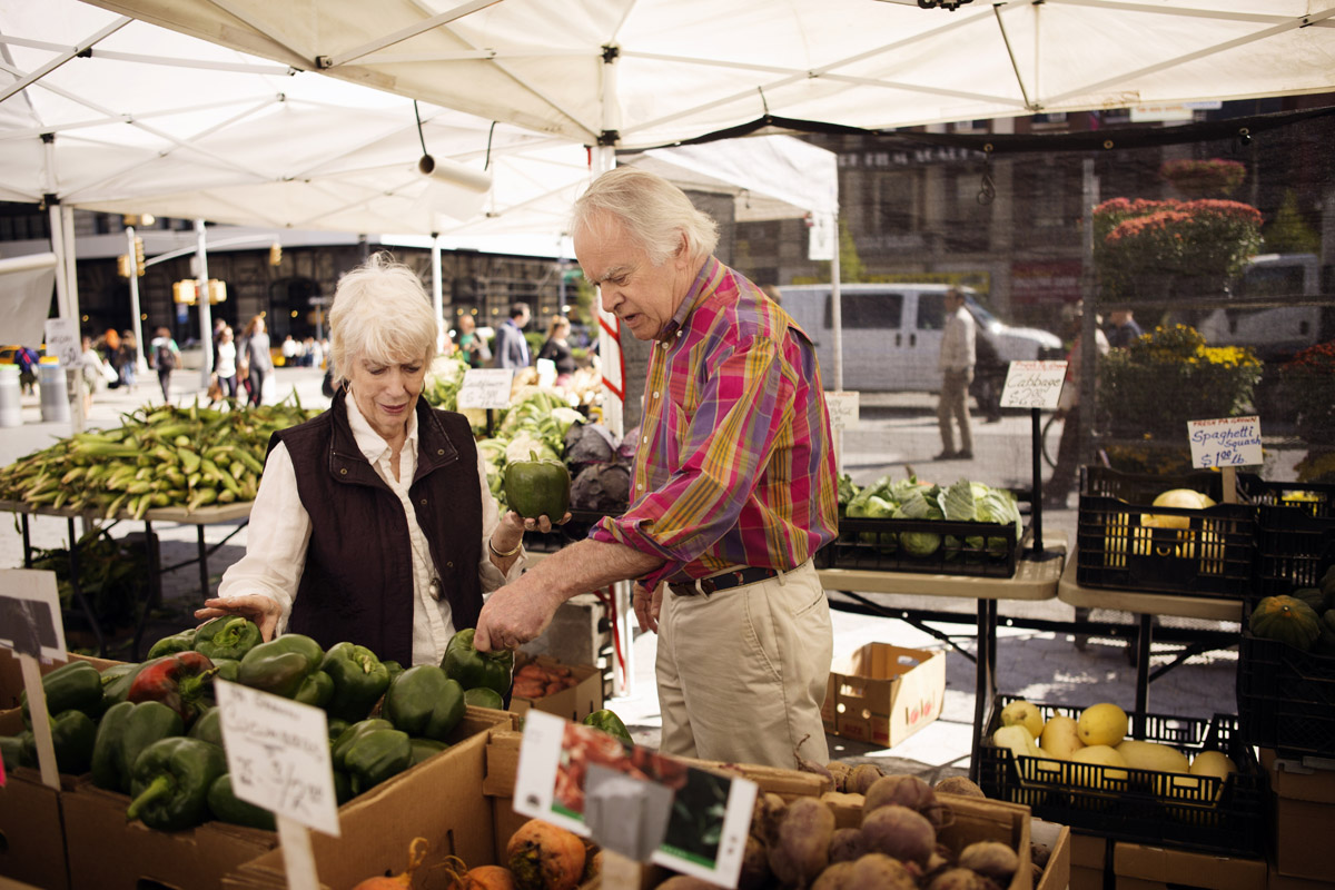 pareja mayor comprando verduras en el mercado callejero