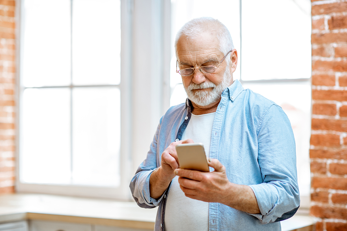 älterer Mann mit Telefon zu Hause